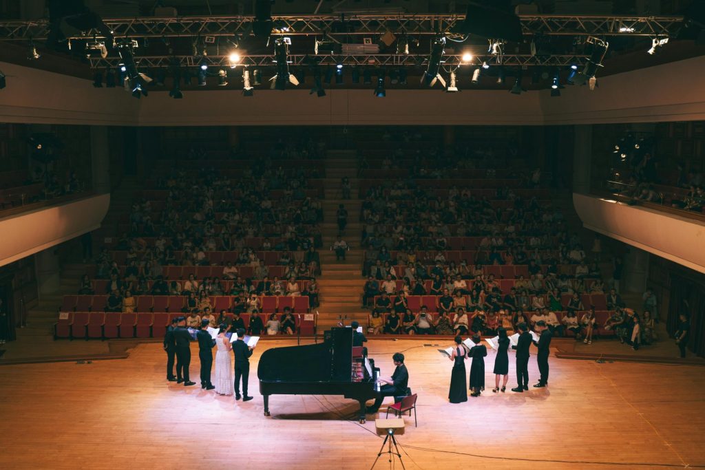 Vibrant classical music concert with pianist and singers on stage.